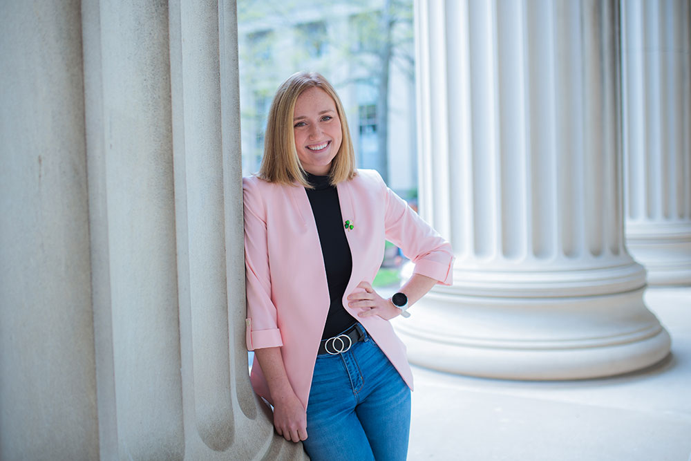 Person leaning agains an architechtural column outdoors at MIT with left hand on hip